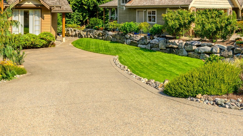 A beautifully landscaped front yard of a home with a gravel driveway