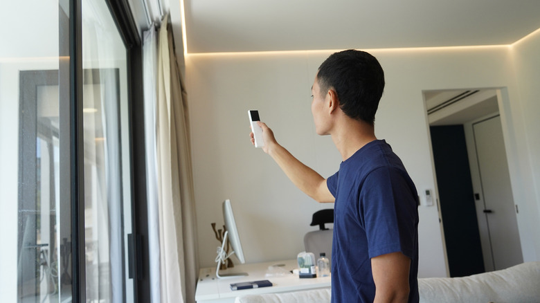 Person using a remote control to shut smart drapery in a home