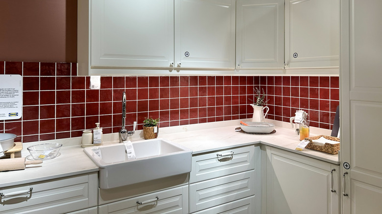 IKEA in-store show kitchen with white cabinets and red backsplash