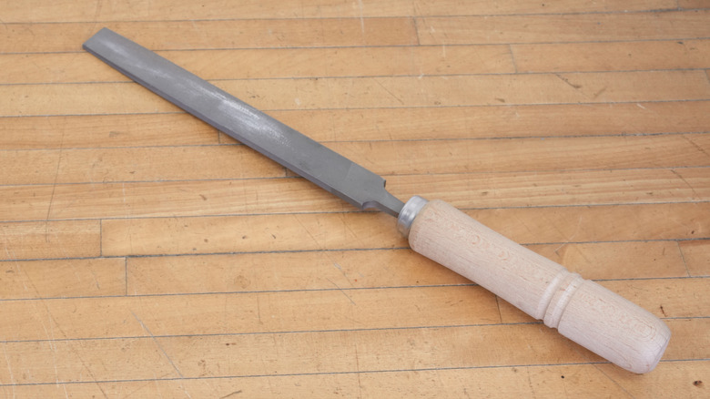 a metal file with a textured handle on a wooden surface