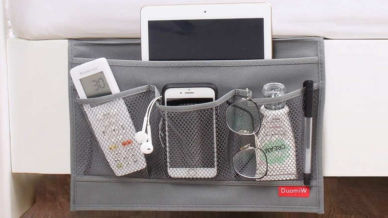 The DuomiW Bedside Storage Organizer hanging from the side of the bed