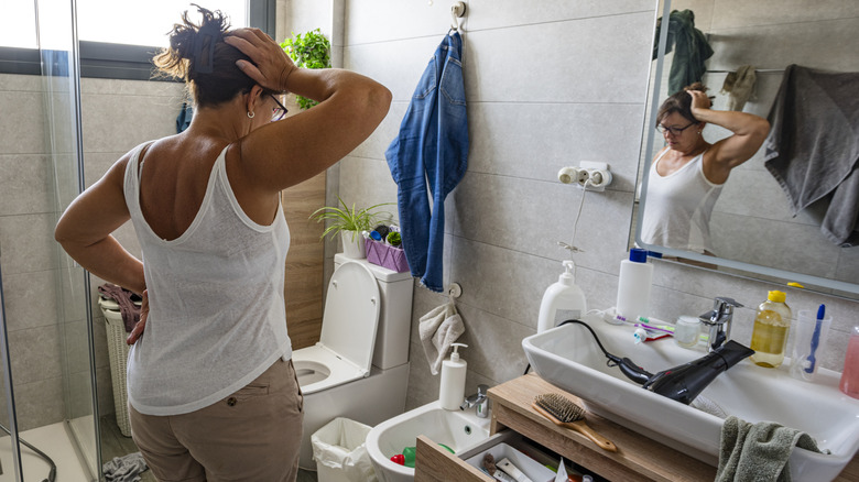 A woman looking overwhelmed in a messy bathroom