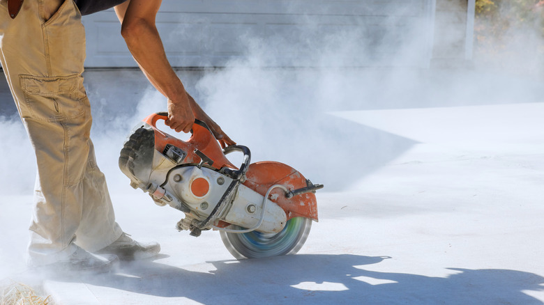 A man saw cutting a concrete driveway