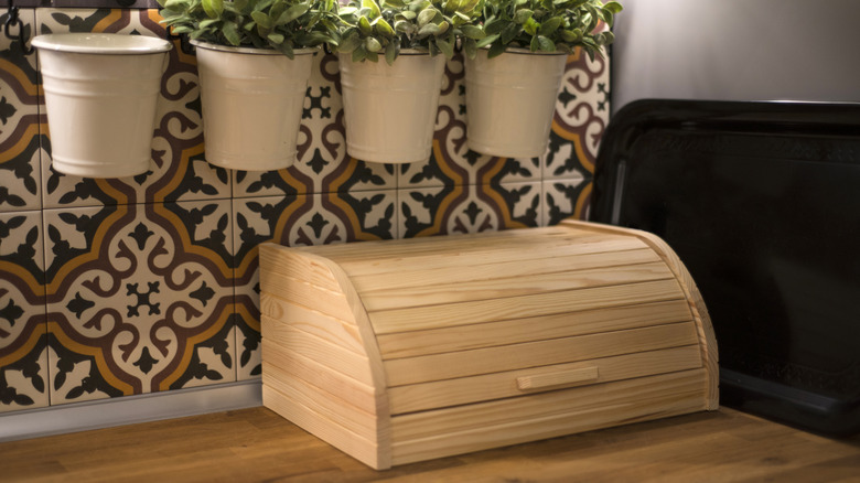 A garage-door style wooden bread box on a kitchen counter