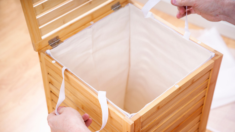 Close-up of a person handling a tall laundry hamper