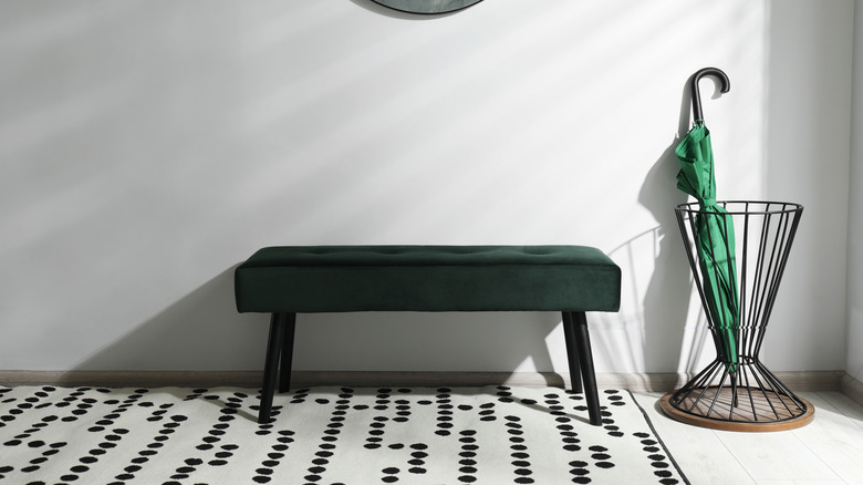 A green umbrella stored in an umbrella stand in an entryway