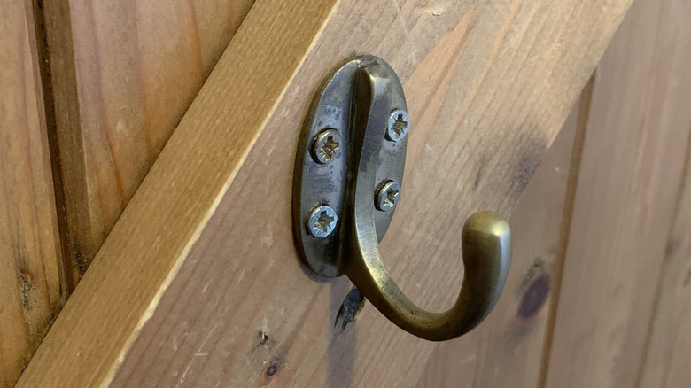 Close-up of a brass hook installed on the back of a wooden door