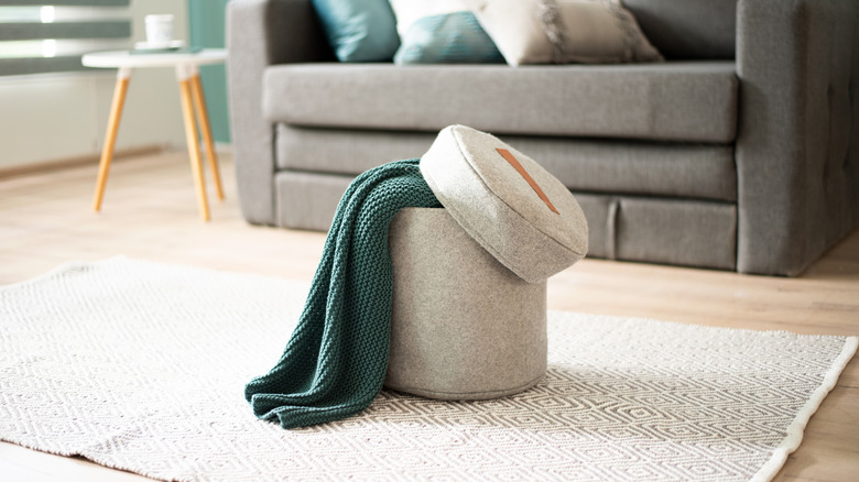 A fabric-upholstered ottoman with a blanket stored inside