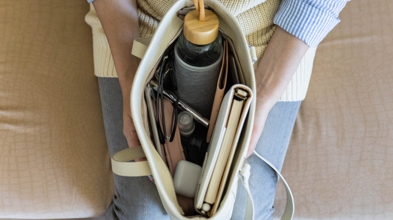 Person holding bag with messy purse interior