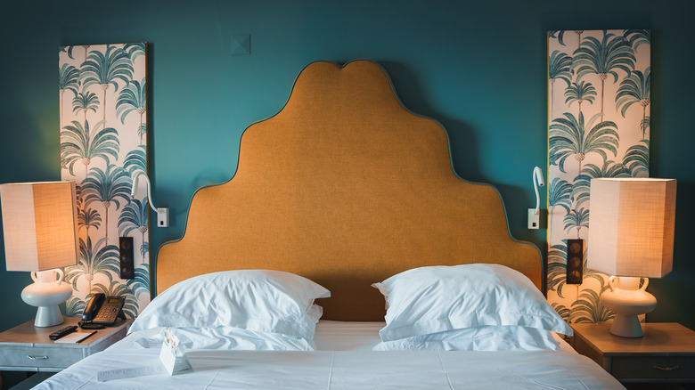 An orange scalloped headboard against a teal bedroom wall
