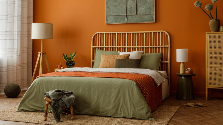 A rattan headboard against an orange terracotta wall in an earth-toned bedroom