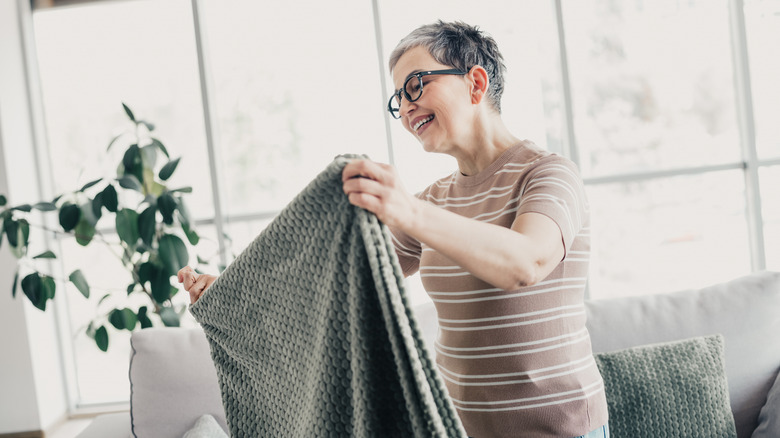 Woman folding a blanket in her living room