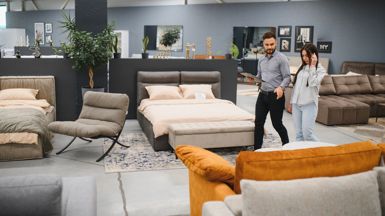 A couple looking round a mattress and bed store to pick out an option.