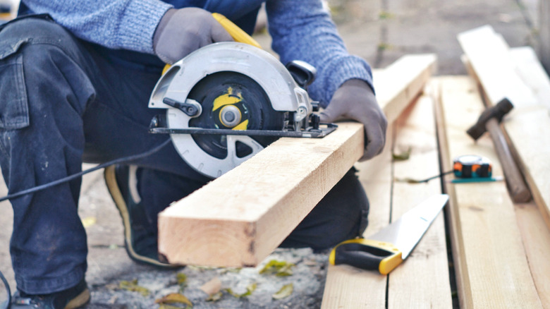 A man using a circular saw to cut 2x4 lumber