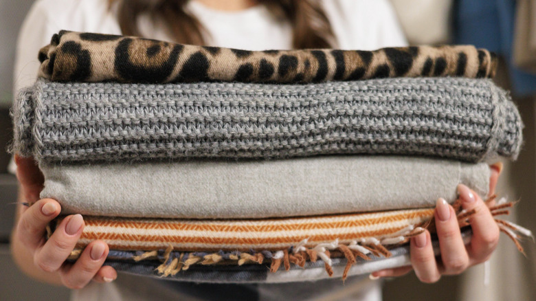 A woman carrying a stack of folded blankets