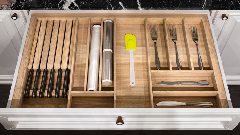 A pulled-out drawer knife holder full of cutlery in a kitchen.