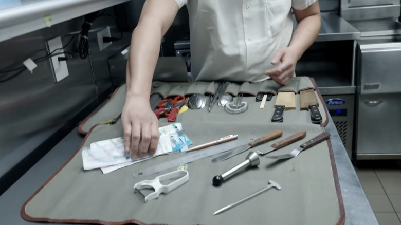 A chef holds a knife roll.