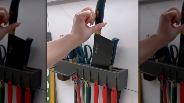 Hand pulling a knife from a wall-mount rack