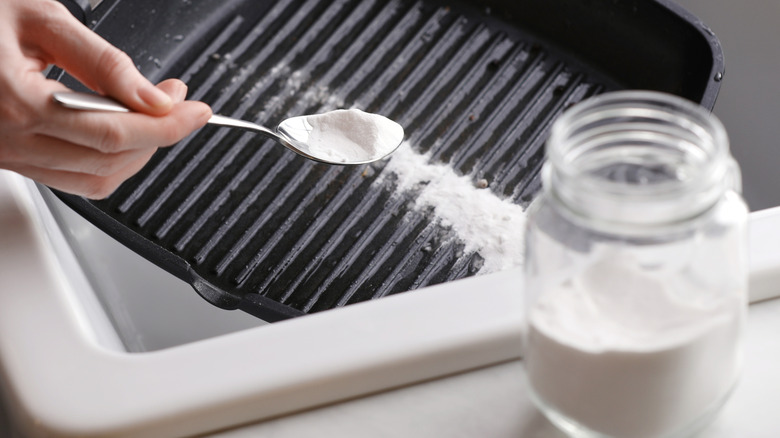 Hand sprinkling baking soda on a pan