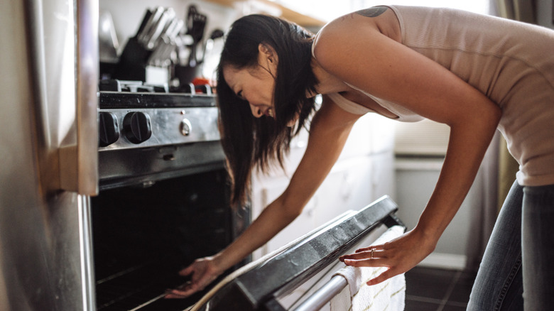 Person placing baking sheet in oven