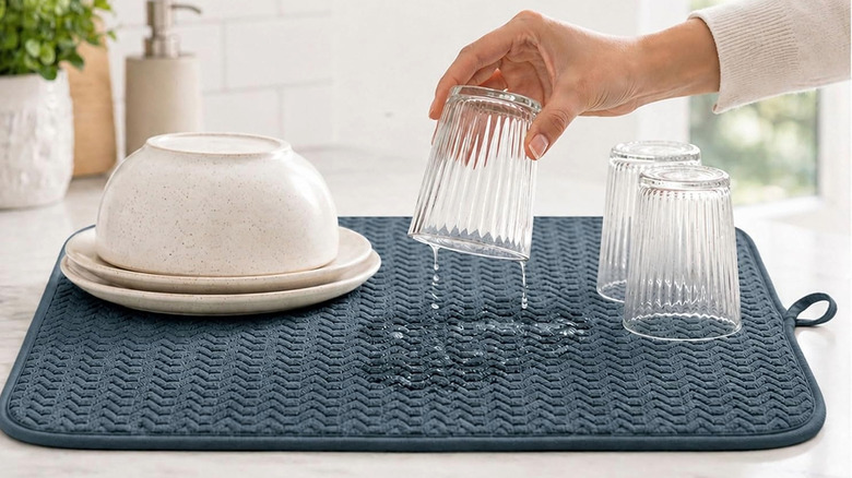 Hand placing a wet glass onto a fabric dish drying mat