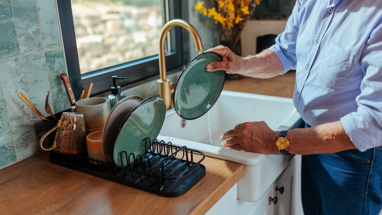 A man putting dishes on a dish drying rack