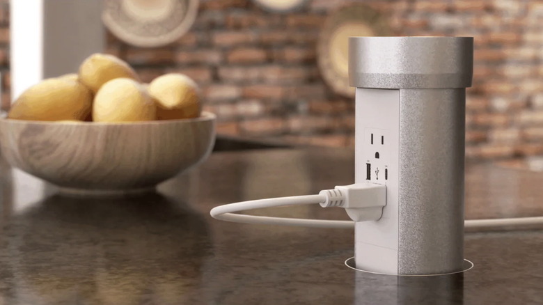 A pop-up outlet on a countertop with a cord plugged in