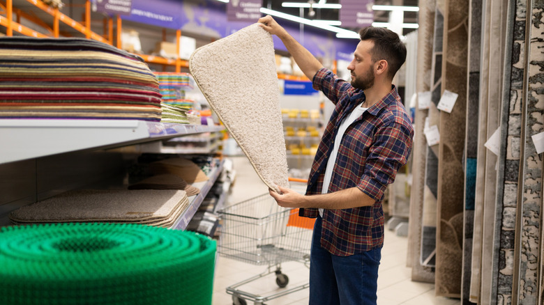 A man shopping for a bath mat in a store