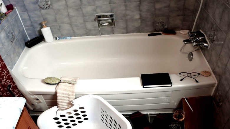 Bathtub with cluttered products lining the rim.