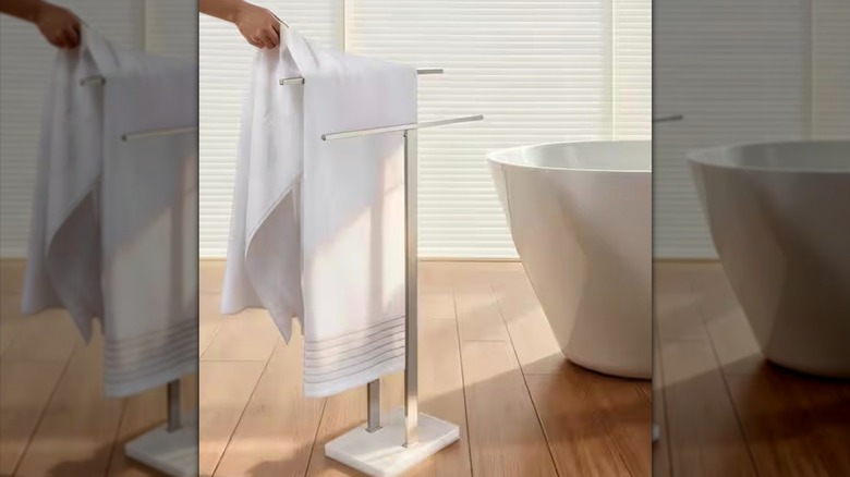 A person retrieving a towel from towel rack in bathroom