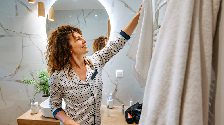 Woman in a small bathroom with towel rack on wall