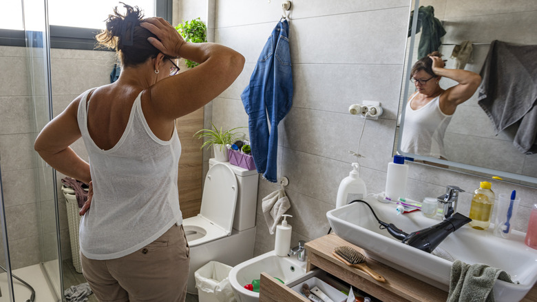A woman looking overwhelmed in a messy bathroom