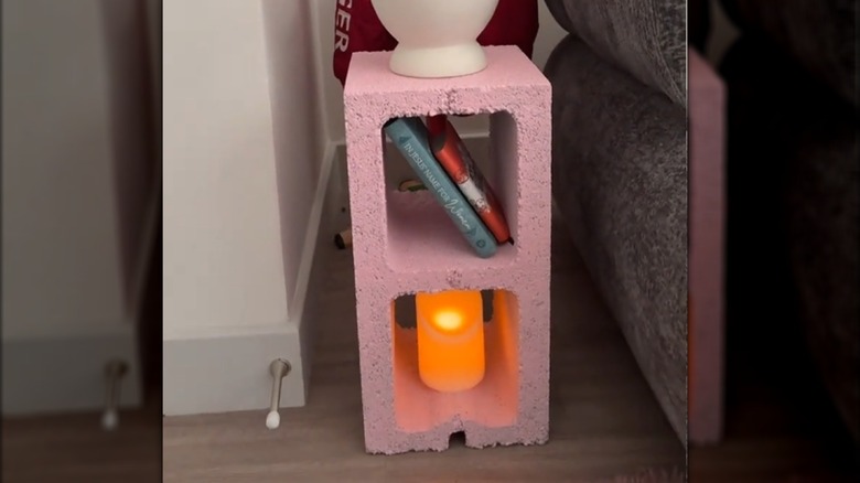 pink painted cinder block used as a side shelf with books and candle on it