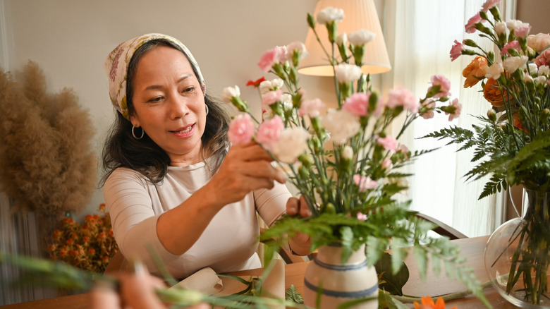 A woman arranging cut flowers in a vase