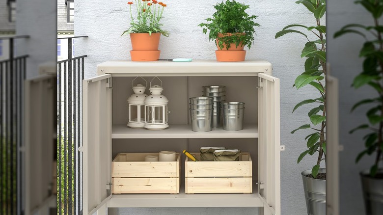 An IKEA KOLBJÖRN cabinet holds garden and yard supplies on a patio.