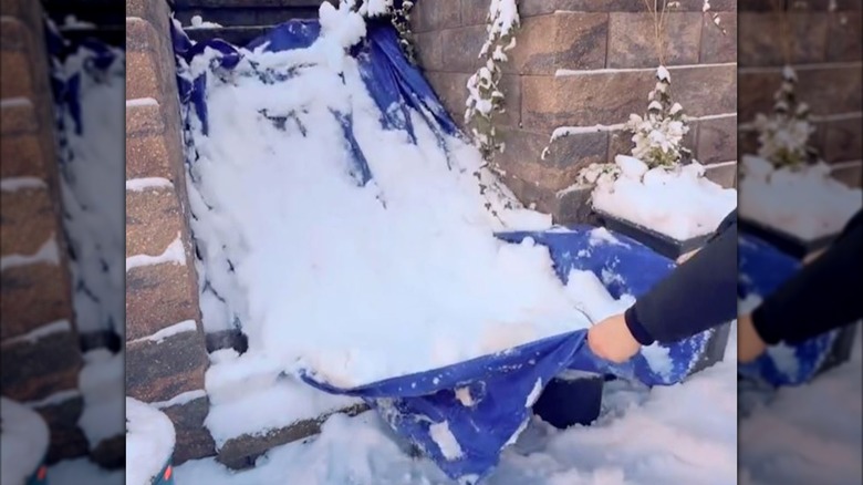 Man pulling snow off of outdoor steps using a tarp