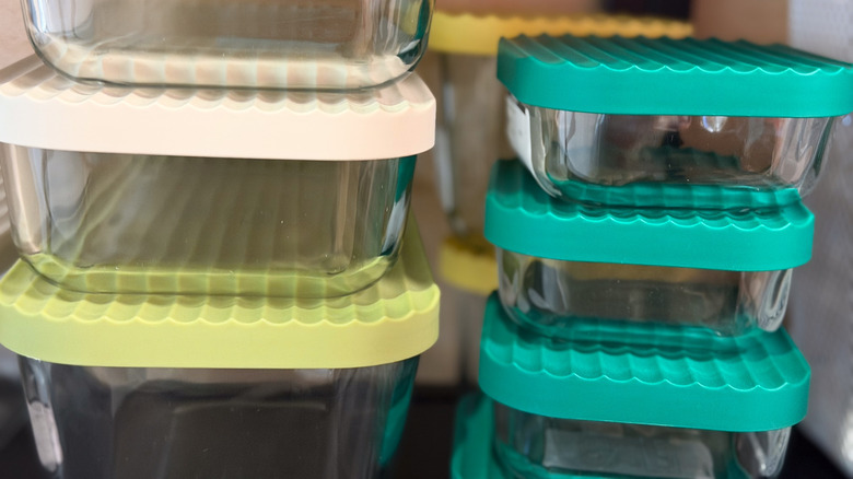 Stacked glass storage containers with colorful silicone lids in teal, yellow, and beige