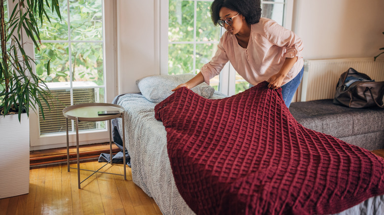 Woman folding a blanket on the back of a couch