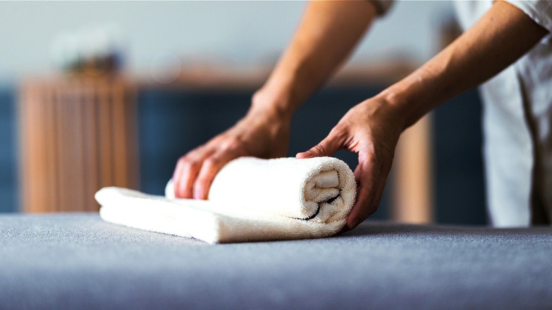 Person rolling a white towel on a blue surface