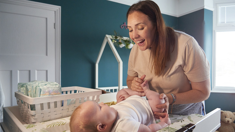 A mother changing her baby on a changing table in a nursery