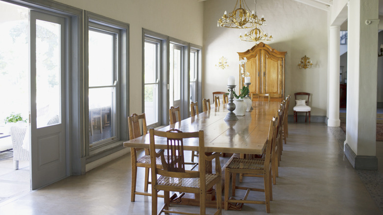 A long, wooden dining table within a big and bright room