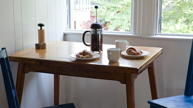 An older simple desk turned into a small dining area with coffee and croissants.