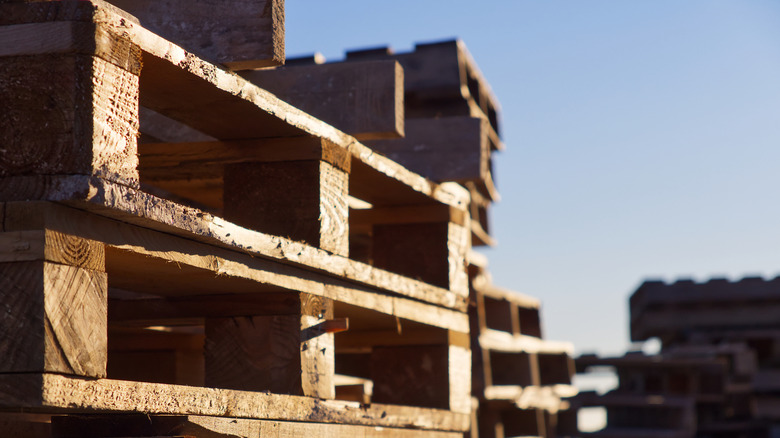 Stacks of wood pallets in the sunlight with the sky in the background