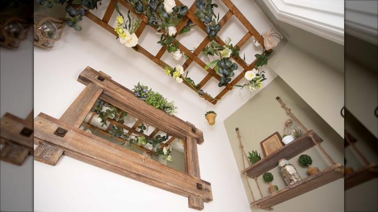 A wood trellis hanging from the ceiling decorated with faux plants