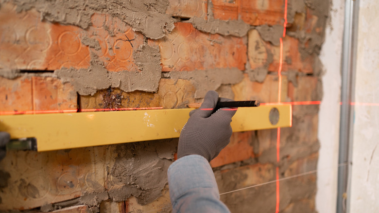 Close-up of a person comparing a spirit level reading to that of a laser level.