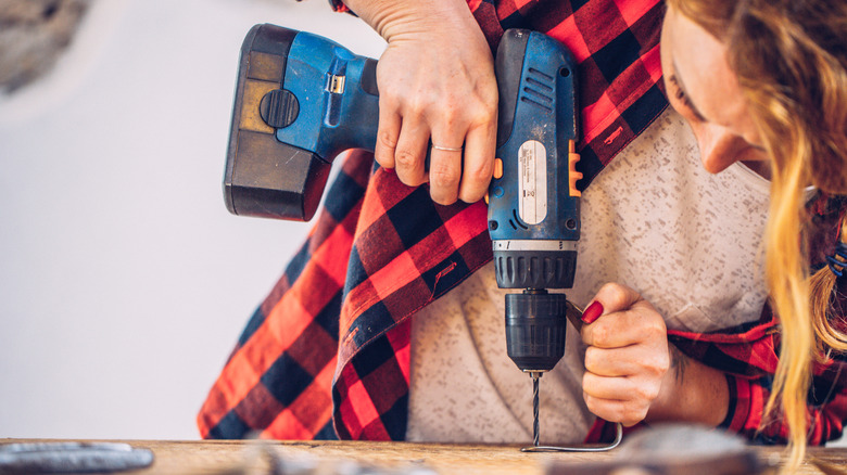 A person using a power drill on wood.
