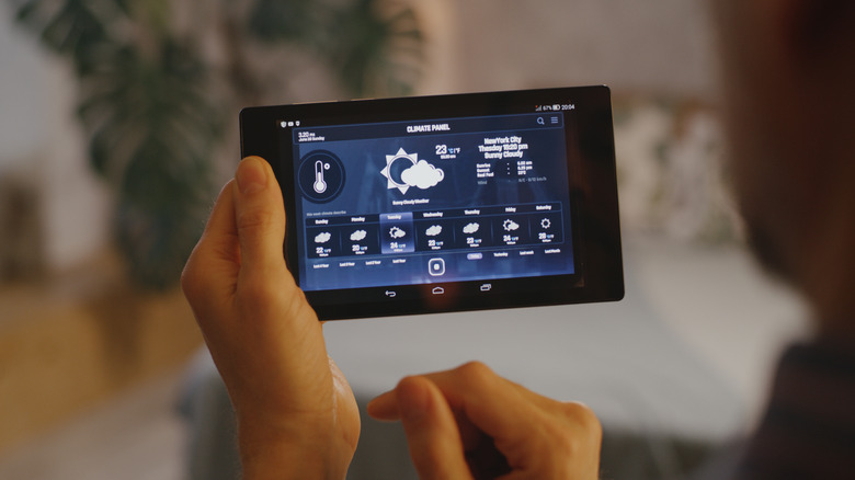 A person checking weather conditions on a smart home hub device
