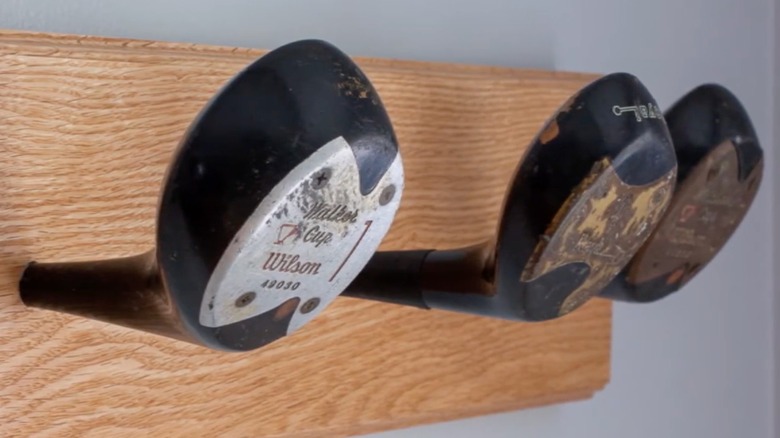 Three golf club heads attached to a wooden board to create a towel rack or coat rack