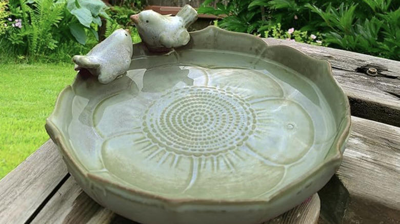 A light green tabletop bird bath dish with two decorative birds and a floral pattern.