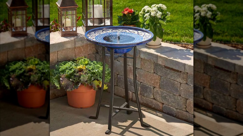 Smart Solar bird bath with blue mosaic detailing and black legs on sunny patio
